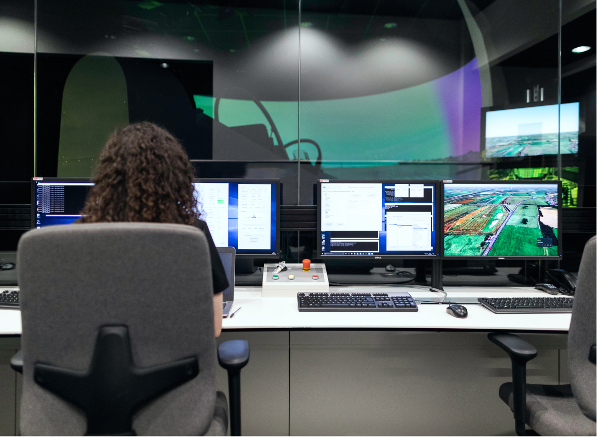 A woman working on a desktop computer with her back to us.